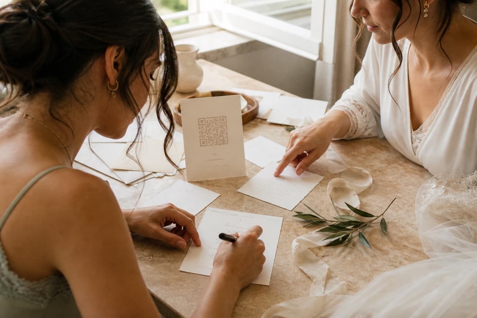Novia y amiga preparando el texto de una tarjeta con código QR para la boda